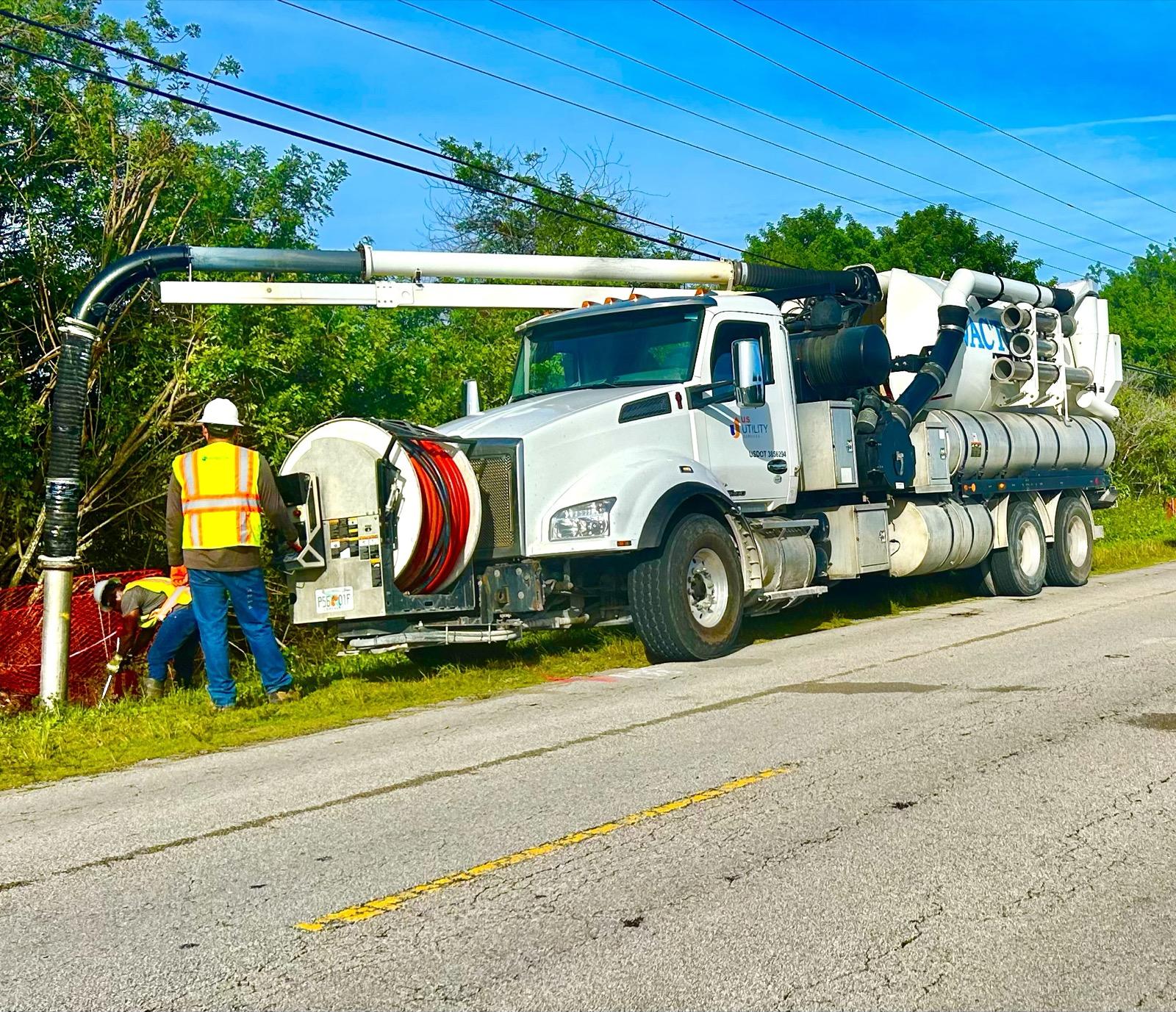 US Utility Services combination jet vac truck with boom extended working a roadside easement in South Florida